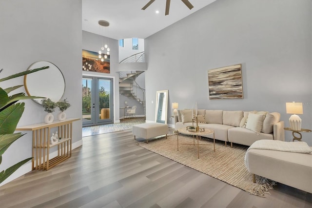 living room with hardwood / wood-style flooring, ceiling fan, french doors, and a high ceiling