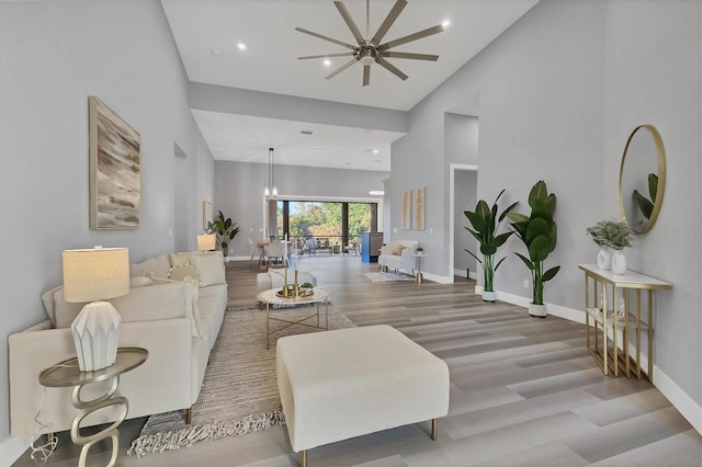 living room with wood-type flooring, high vaulted ceiling, and ceiling fan