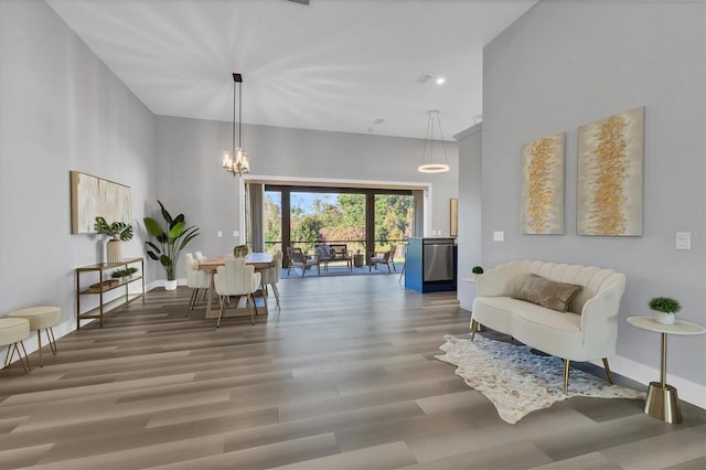 sitting room with hardwood / wood-style flooring, a chandelier, and a high ceiling