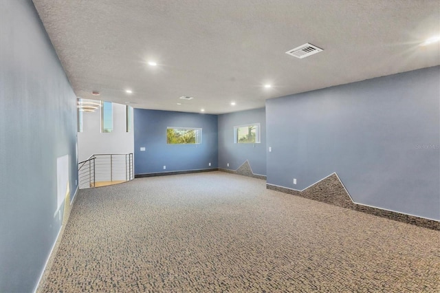 carpeted empty room featuring a textured ceiling