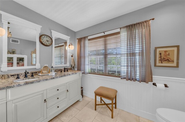 7820 Seville Cir, Bradenton, FL 34209 - full bath with double vanity, wainscoting, tile patterned flooring, and toilet