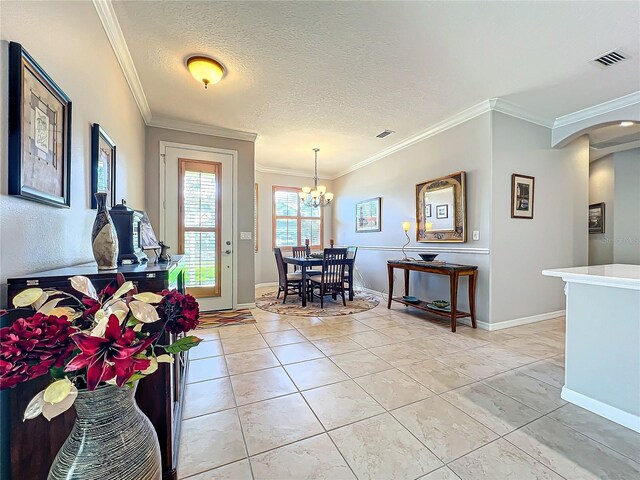 foyer entrance with light tile patterned floors, visible vents, a textured ceiling, and crown molding