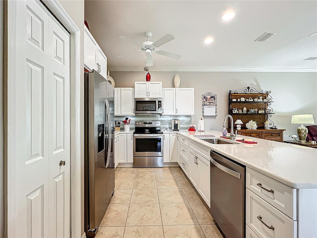 kitchen featuring a sink, tasteful backsplash, appliances with stainless steel finishes, a peninsula, and crown molding