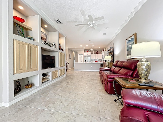 living room with visible vents, built in shelves, a textured ceiling, and ornamental molding