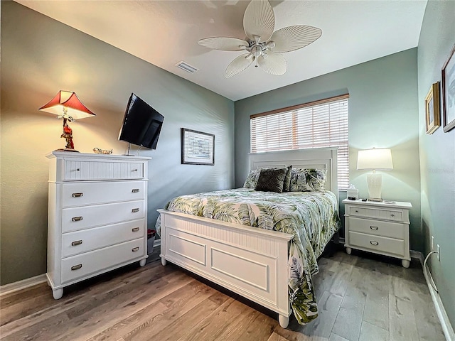 bedroom featuring visible vents, baseboards, a ceiling fan, and wood finished floors