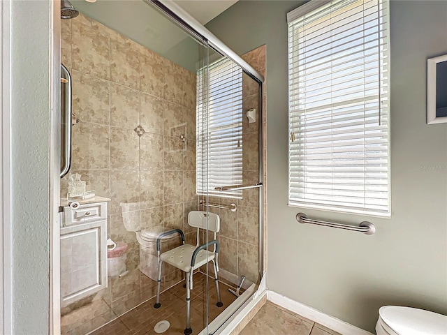 bathroom featuring tile patterned flooring, toilet, baseboards, and a stall shower