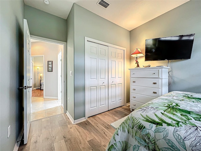 bedroom with visible vents, baseboards, vaulted ceiling, light wood-style floors, and a closet