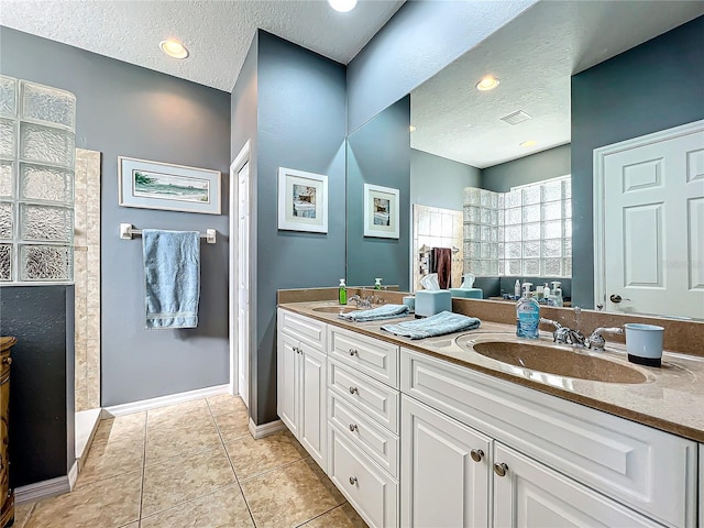 bathroom with tile patterned floors, double vanity, a textured ceiling, and a sink