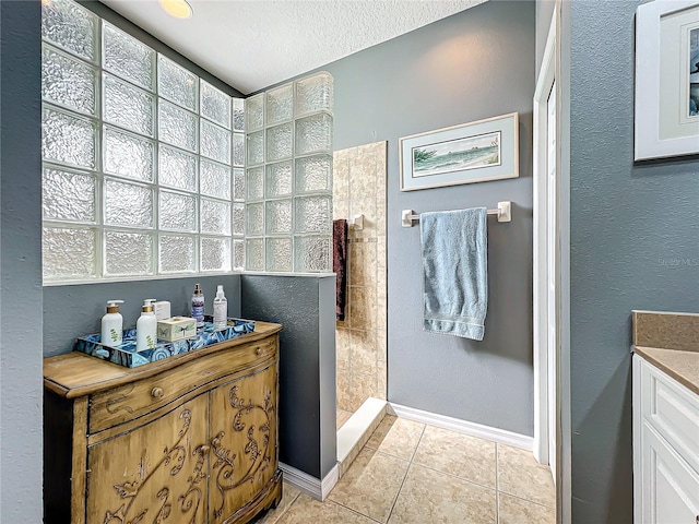 bathroom with tile patterned flooring, a walk in shower, baseboards, vanity, and a textured ceiling