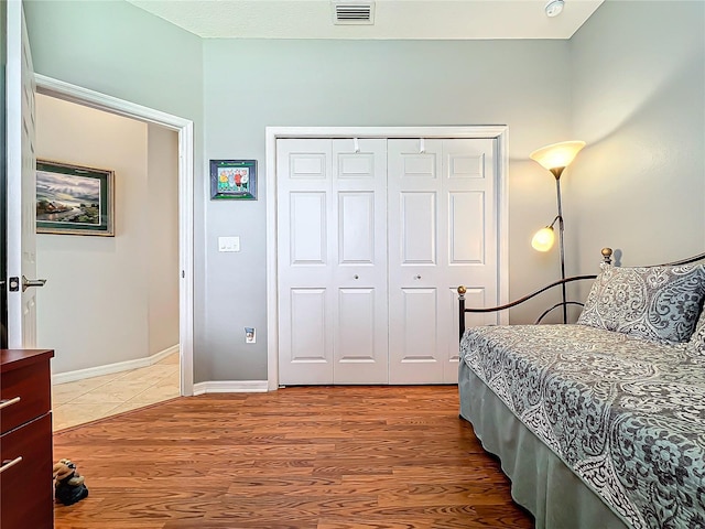 bedroom featuring light wood finished floors, visible vents, baseboards, and a closet