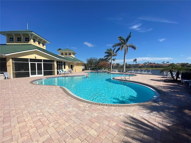 community pool featuring a sunroom and a patio area