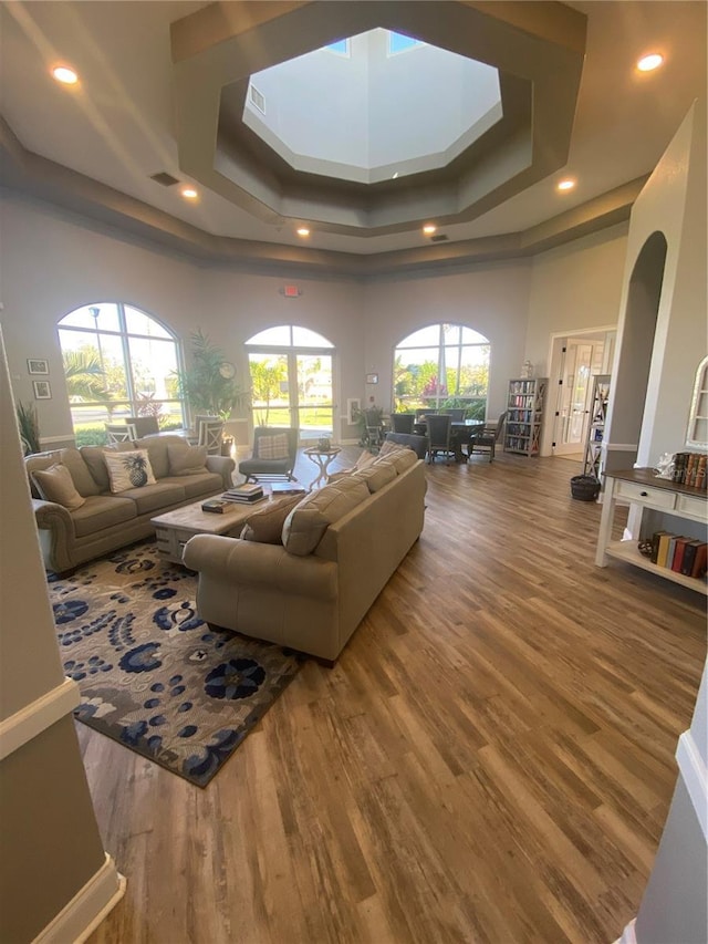 living area featuring a raised ceiling, recessed lighting, wood finished floors, and visible vents