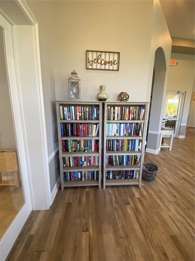 interior space featuring arched walkways, baseboards, and wood finished floors