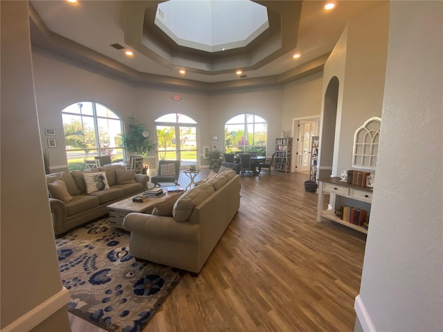 living area featuring wood finished floors, visible vents, a high ceiling, recessed lighting, and a raised ceiling