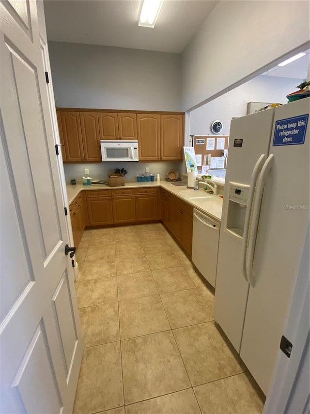 kitchen with white appliances, light tile patterned floors, light countertops, and a sink