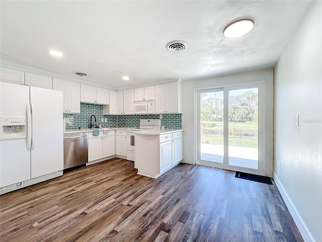 kitchen featuring sink, white cabinets, decorative backsplash, hardwood / wood-style flooring, and white appliances