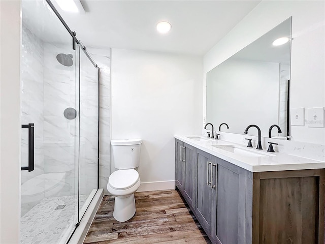 bathroom featuring hardwood / wood-style flooring, vanity, toilet, and a shower with shower door