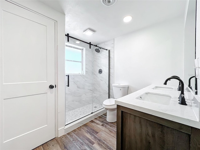 bathroom with vanity, hardwood / wood-style flooring, a shower with door, and toilet