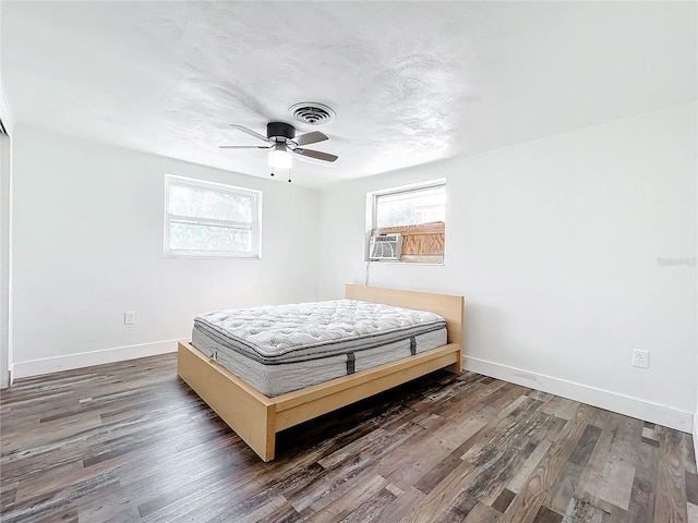 unfurnished bedroom featuring multiple windows, cooling unit, dark wood-type flooring, and ceiling fan