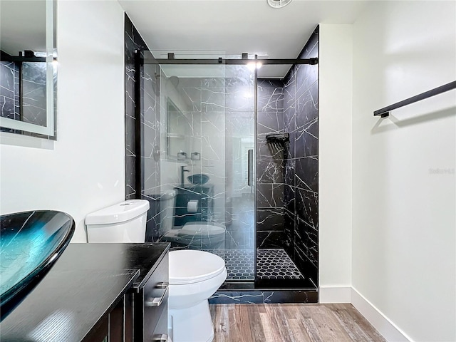 bathroom featuring a shower with door, vanity, hardwood / wood-style floors, and toilet