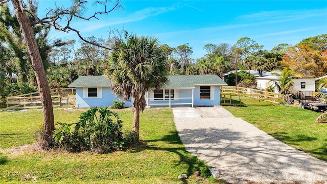 ranch-style home featuring a front yard, fence, driveway, and stucco siding