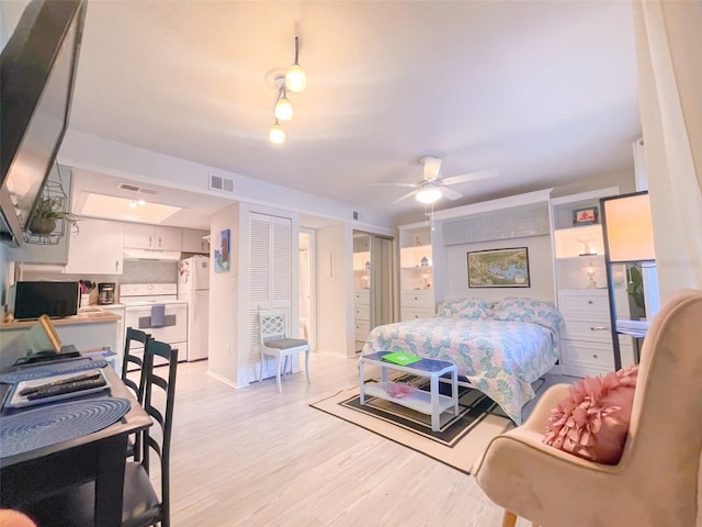 bedroom with white fridge and light hardwood / wood-style floors