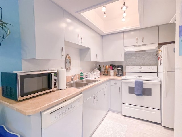 kitchen featuring white cabinetry, sink, light hardwood / wood-style floors, a raised ceiling, and white appliances