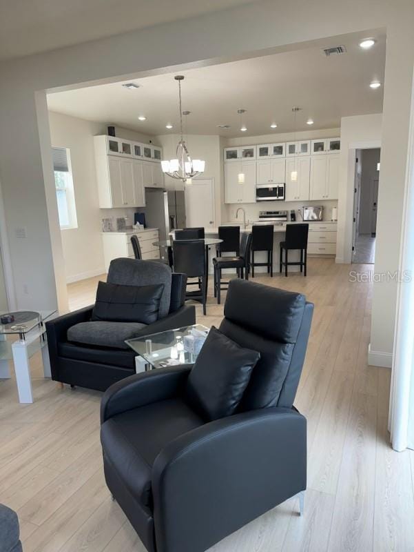 living room with a notable chandelier and light hardwood / wood-style flooring