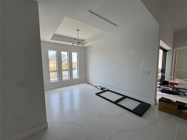 empty room featuring a raised ceiling and an inviting chandelier