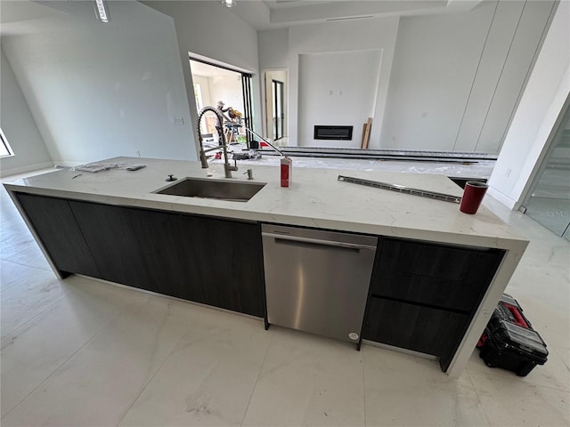 kitchen with dishwasher, sink, light stone countertops, and a center island with sink