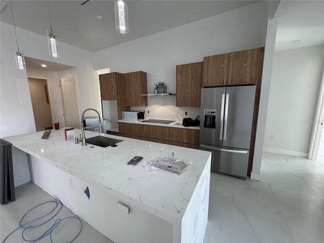 kitchen with a kitchen island with sink, hanging light fixtures, sink, and stainless steel refrigerator with ice dispenser