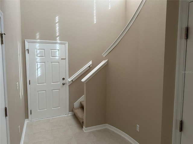foyer with light tile patterned floors, baseboards, and stairway
