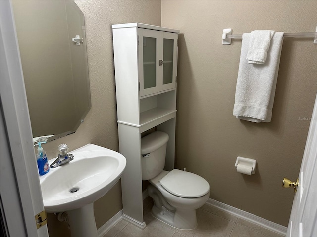 half bath featuring toilet, tile patterned floors, and a sink