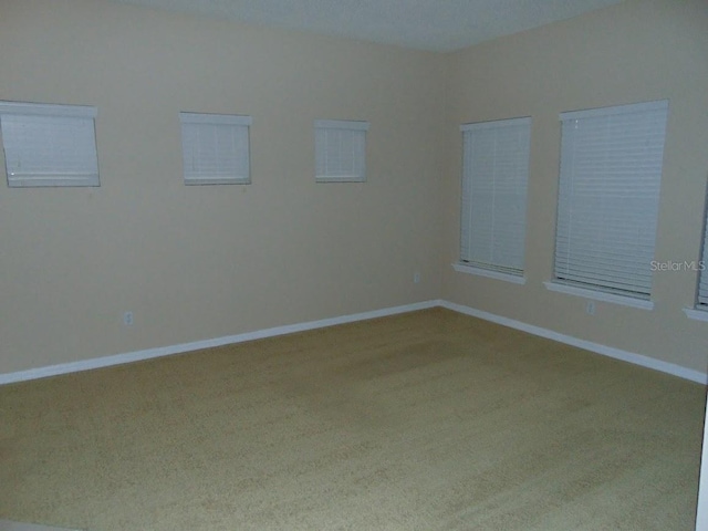 carpeted spare room featuring baseboards