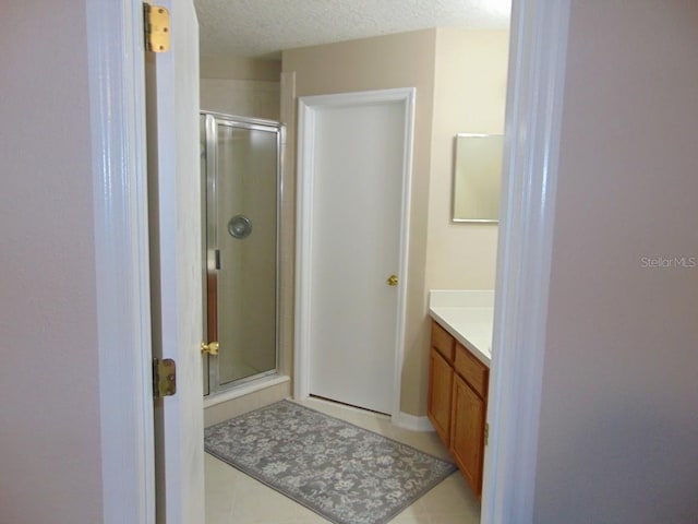 bathroom with a shower stall, vanity, tile patterned flooring, and a textured ceiling