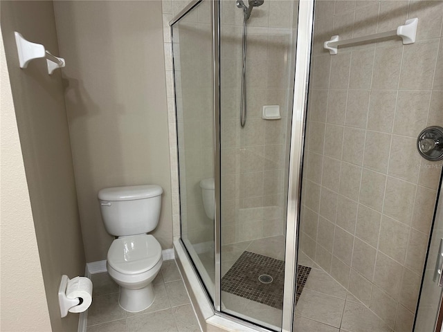 full bath with a shower stall, toilet, tile patterned flooring, and baseboards