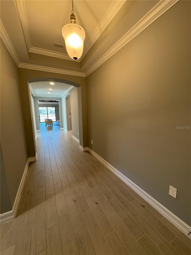 hallway with ornamental molding, hardwood / wood-style floors, and a tray ceiling