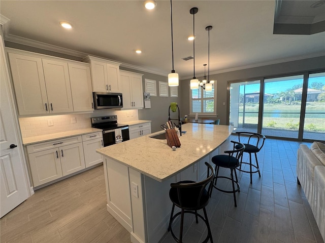 kitchen featuring electric stove, a kitchen island with sink, sink, and white cabinets