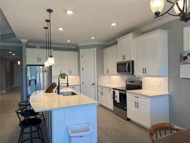 kitchen featuring white cabinetry, an island with sink, sink, hanging light fixtures, and stainless steel appliances