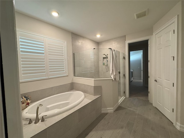 bathroom featuring hardwood / wood-style flooring and plus walk in shower