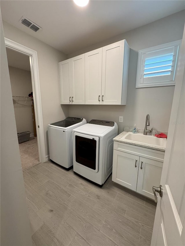 laundry area with separate washer and dryer, sink, and cabinets