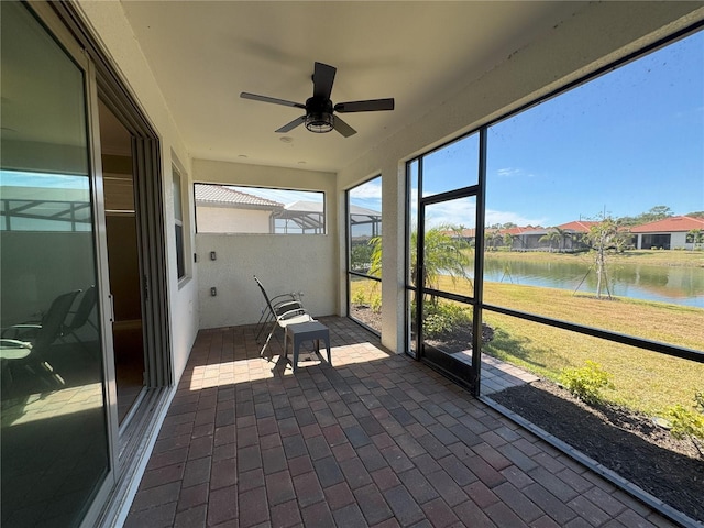 unfurnished sunroom with a water view and ceiling fan