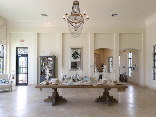 interior space with ornamental molding, a high ceiling, and a notable chandelier