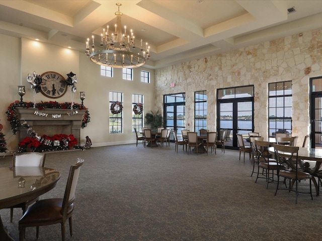 carpeted dining space featuring beamed ceiling, coffered ceiling, a towering ceiling, and french doors