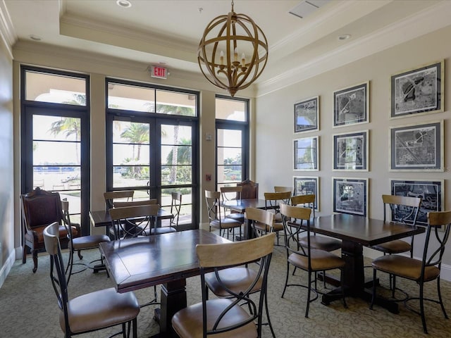 dining area with french doors, crown molding, a raised ceiling, and an inviting chandelier