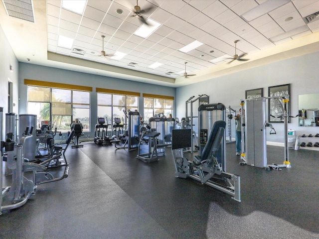 gym with a towering ceiling, a paneled ceiling, and ceiling fan