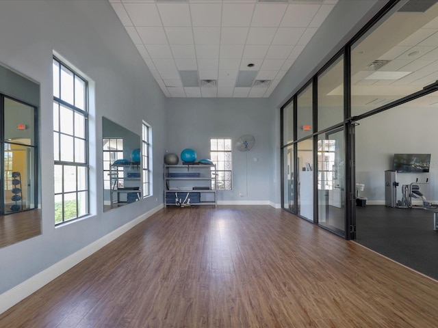 unfurnished living room featuring a wealth of natural light, a towering ceiling, and hardwood / wood-style floors