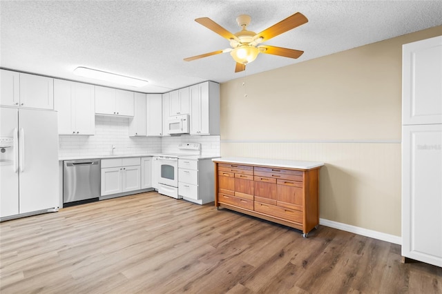 kitchen with white appliances, light hardwood / wood-style floors, and white cabinets