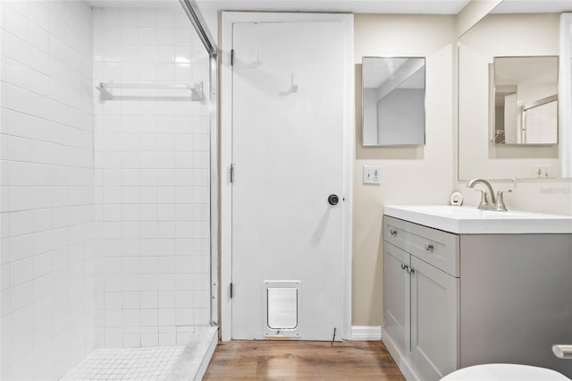 bathroom with vanity, hardwood / wood-style floors, and tiled shower