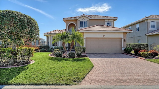 mediterranean / spanish-style home featuring a garage, stucco siding, a tile roof, decorative driveway, and a front yard